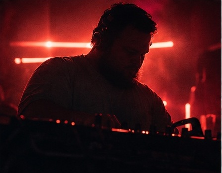 NØXIM silhouetted in red club lighting